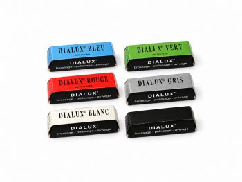 Six Dialux polishing compound bars in blue, green, red, grey, white and black packaging on a white background.