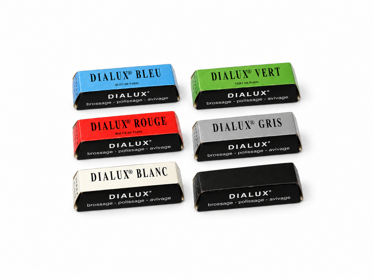 Six Dialux polishing compound bars in blue, green, red, grey, white and black packaging on a white background.
